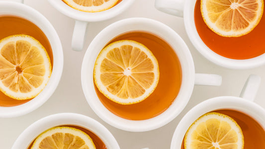 White cups of hot tea with lemon slices on a white surface, top view close-up