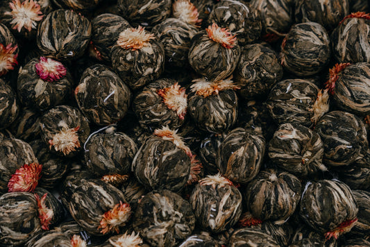 Close-up of dried blooming tea balls with dark leaves and orange and pink flower tops